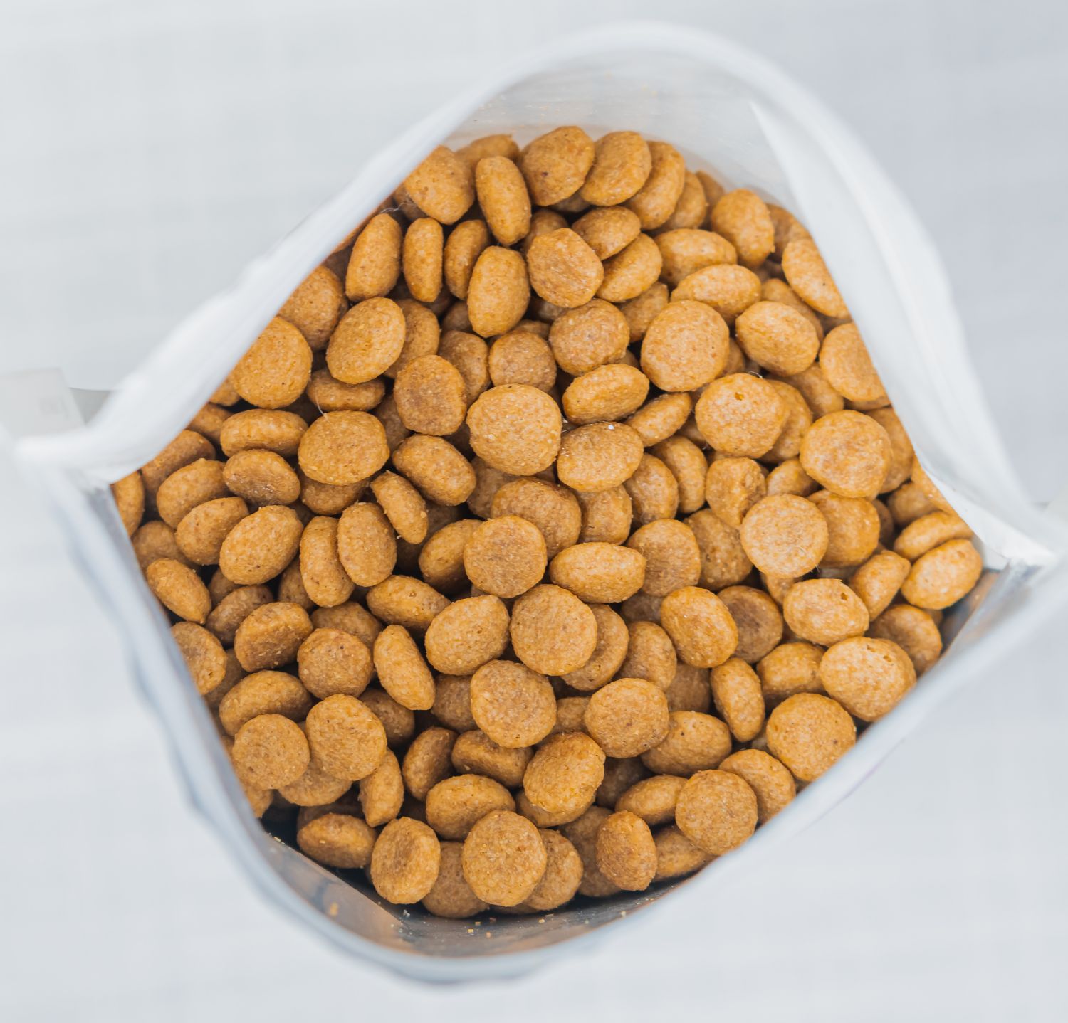 Åben pose med brune kugleformede tørfoderpellets til kæledyr